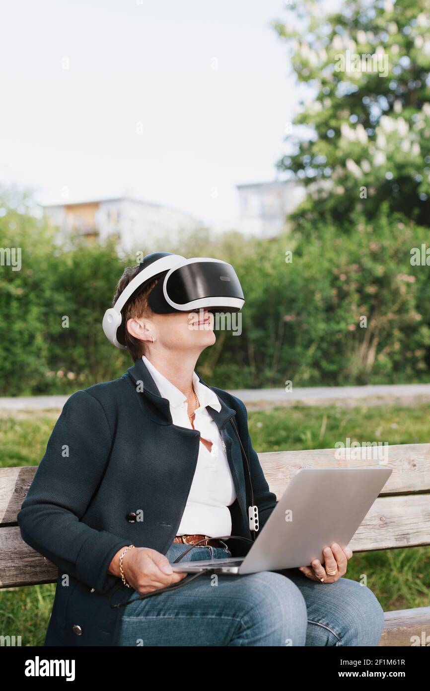 Woman on bench using VR headset Stock Photo