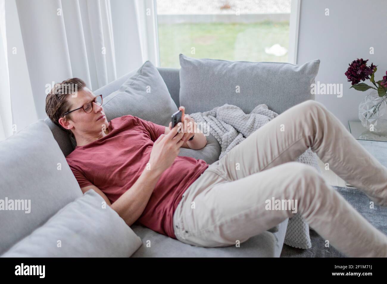 Man on sofa using cell phone Stock Photo