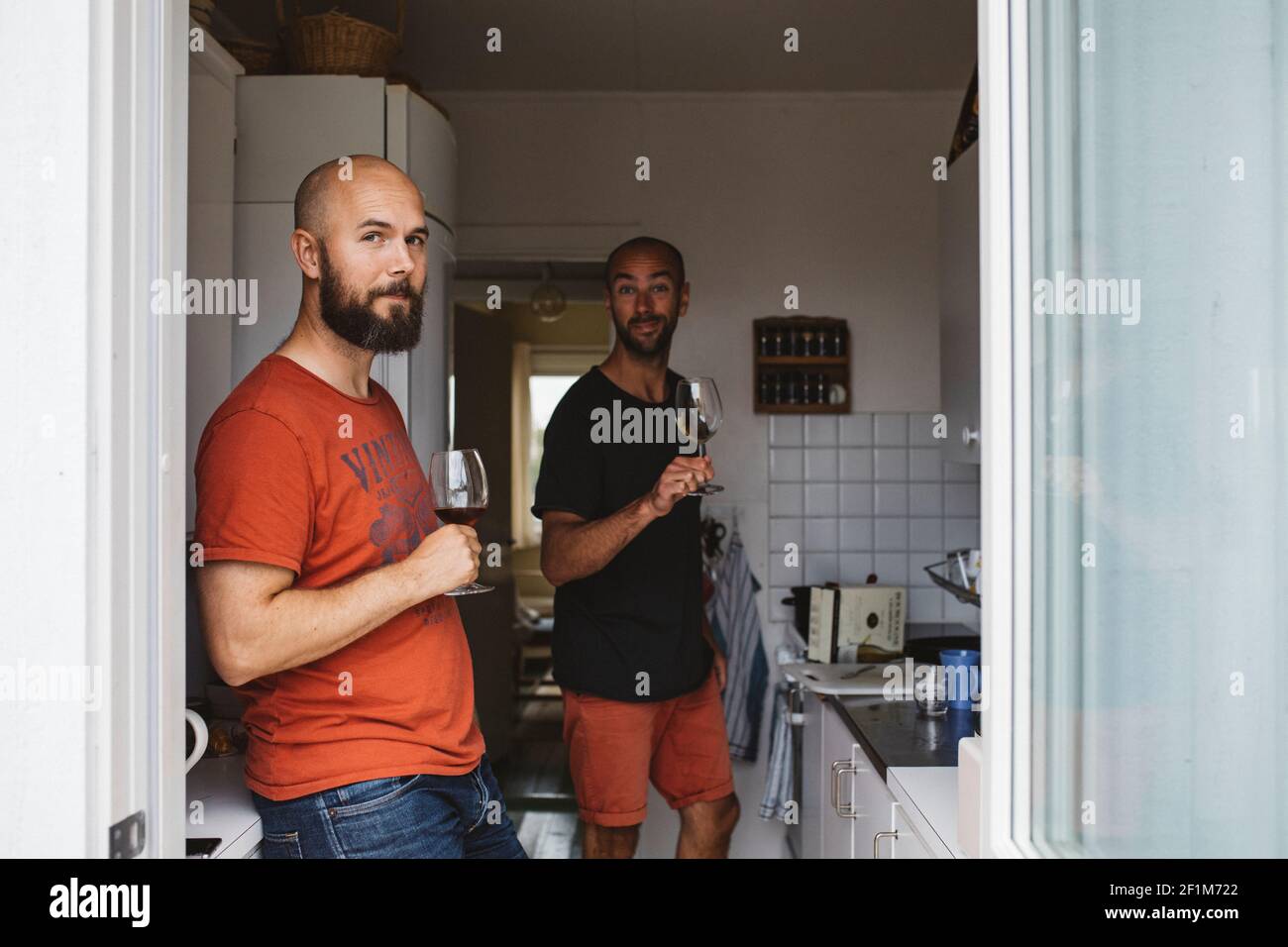Men holding wineglasses in kitchen Stock Photo