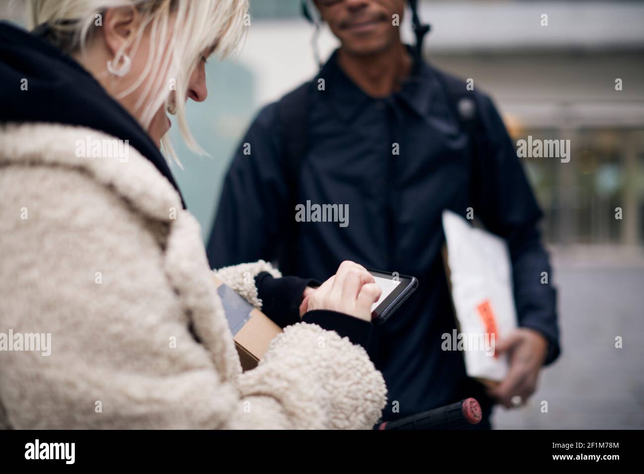 Bicycle courier taking sign from female customer while delivering package Stock Photo