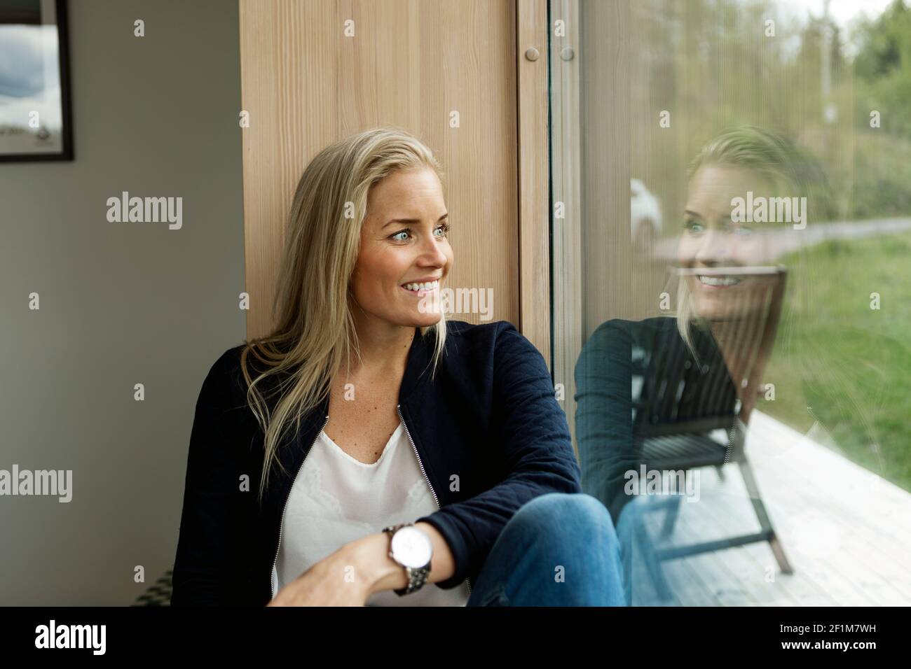 Blond woman looking through window Stock Photo