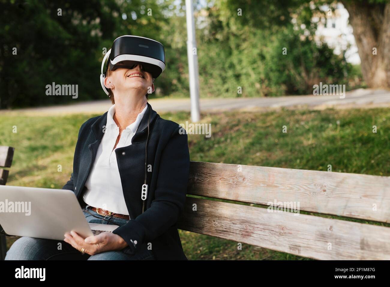 Woman on bench using VR headset Stock Photo