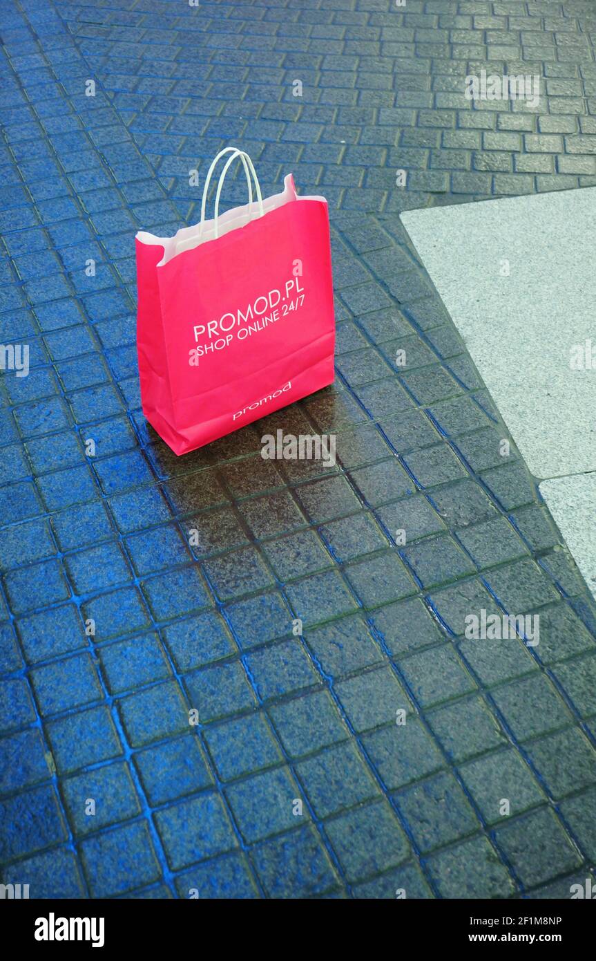 POZNAN, POLAND - Dec 01, 2013: Pink paper shopping bag laying on a floor of a mall Stock Photo