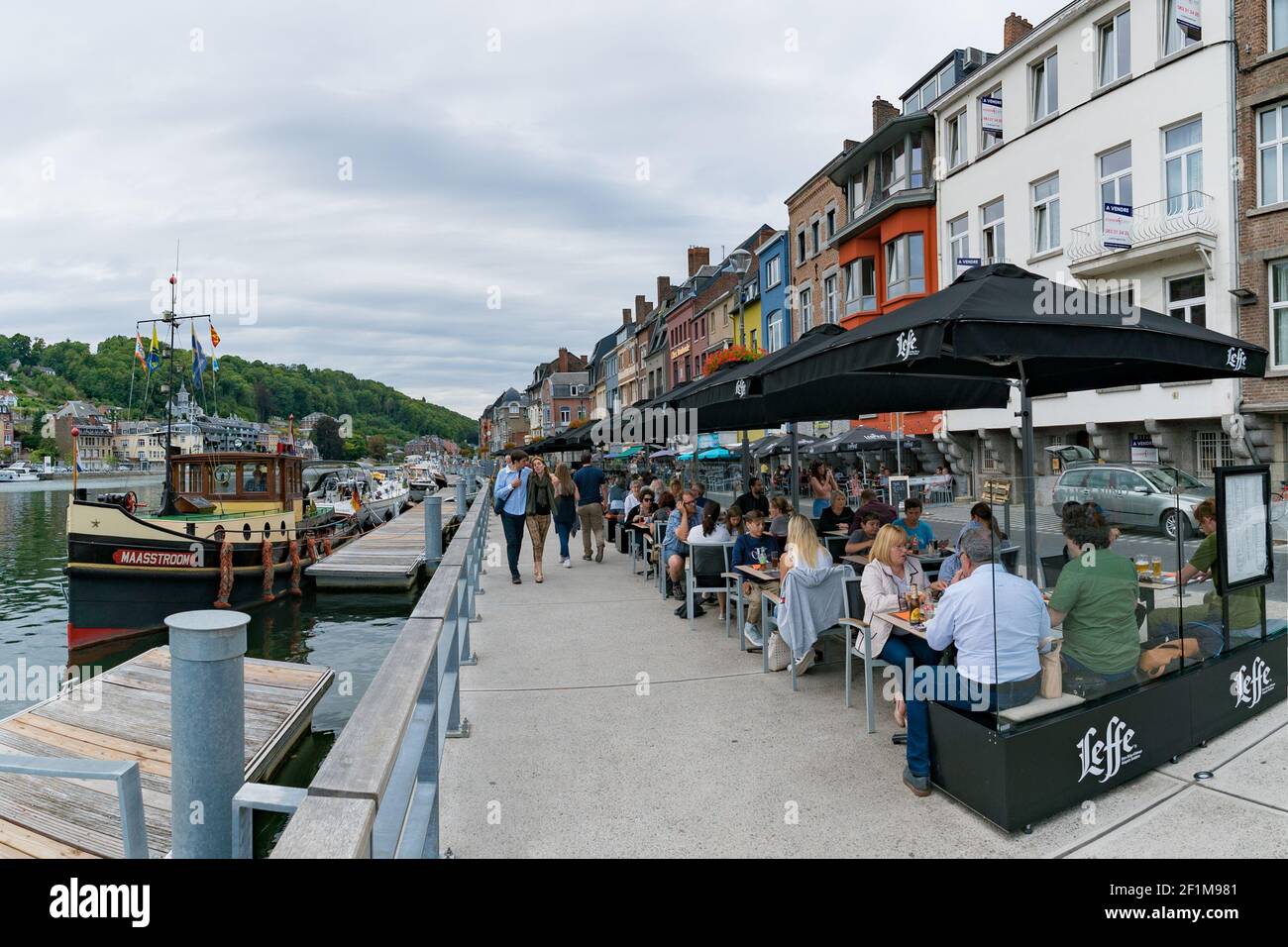 Tourists enjoying a meal out in the river front restaurants of Dinant on the Maas River with passers Stock Photo
