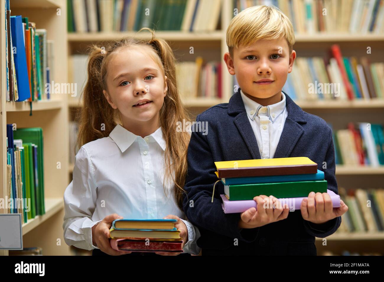 boy and girl prepared for school, they stand holding stack of books in ...