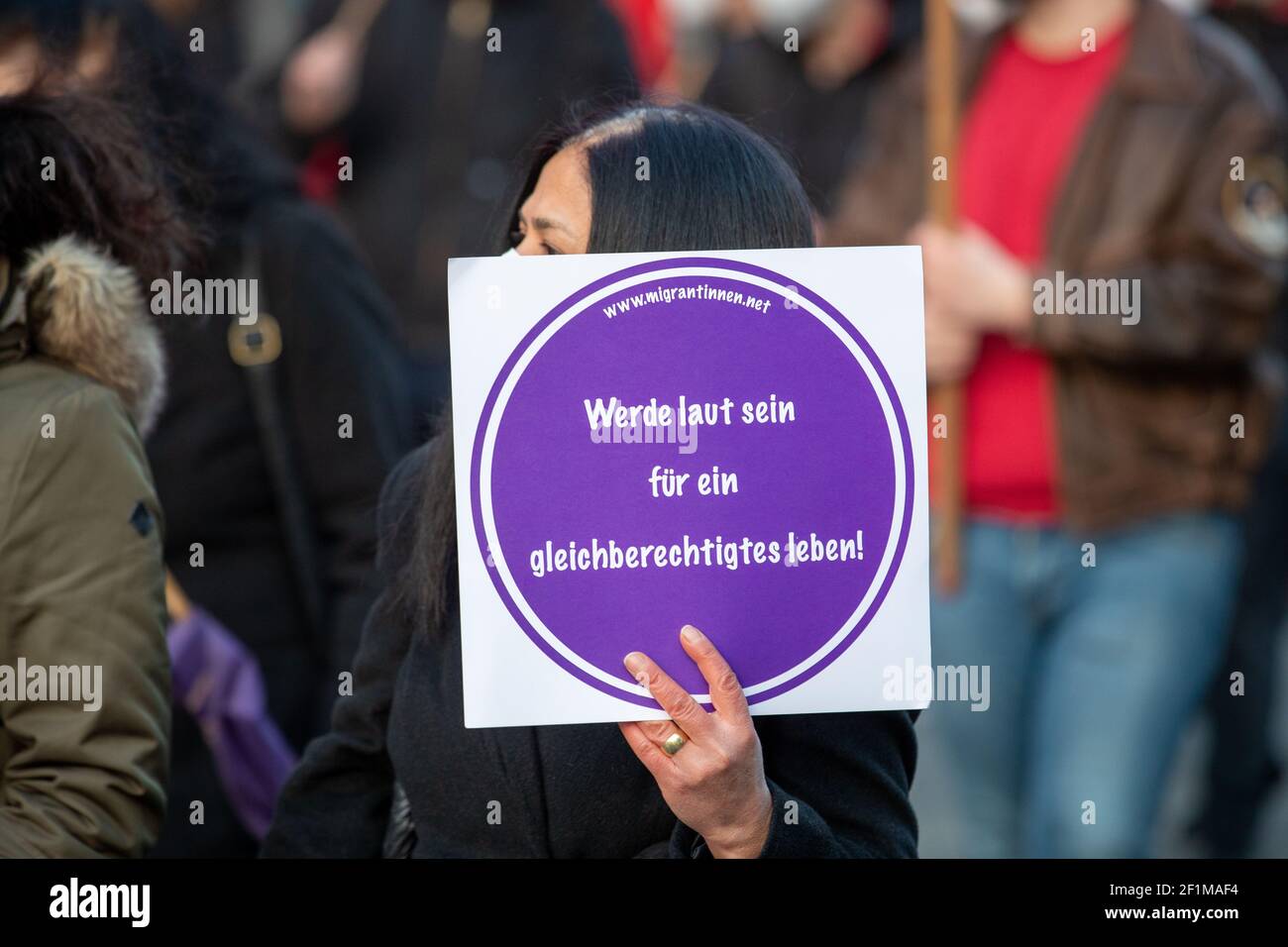 Demonstrantin hält Schild mit der Aufschrift: ' migrantinnen.net Werde laut sein für ein gleichberechtigtes Leben! ' Am Weltfrauentag, dem 8.3.2021 haben sich in München um die 1000 Menschen versammelt, um für das Recht auf Schwangerschaftsabbrüche, gegen den Gender-Pay-Gap, Sexismus und Femizide zu demonstrieren. - On the international women's day March 8 2021 around 1000 people joined a demonstration in Munich, Germany to protest against sexism, the gender-pay-gap and femicides. (Photo by Alexander Pohl/Sipa USA) Stock Photo