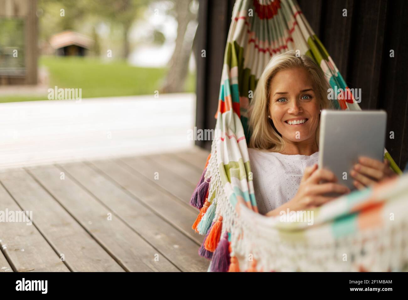 Woman lying in hammock and using tablet Stock Photo