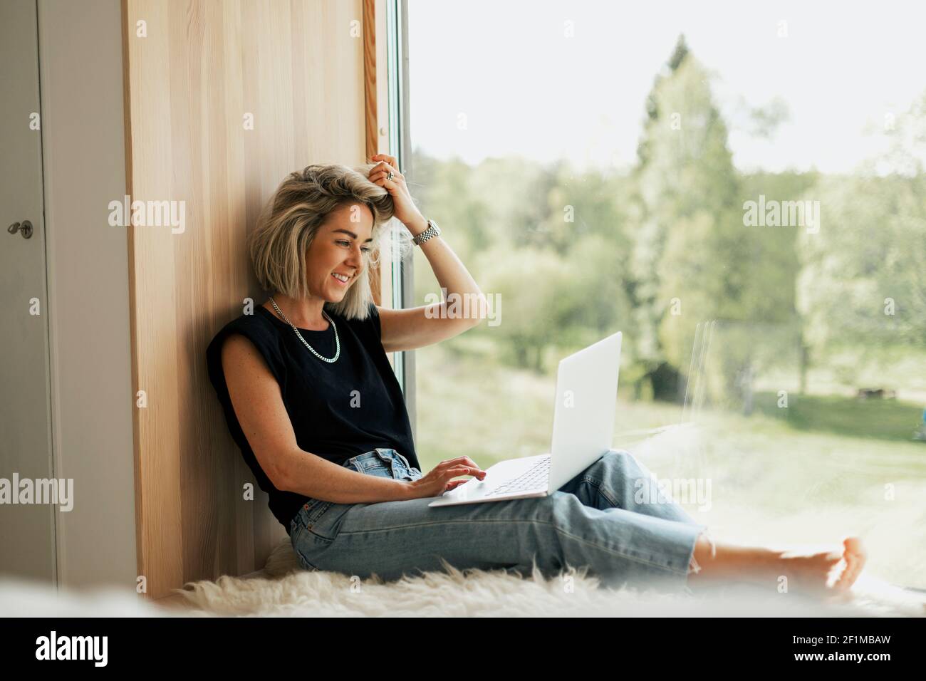 Woman using laptop near window Stock Photo