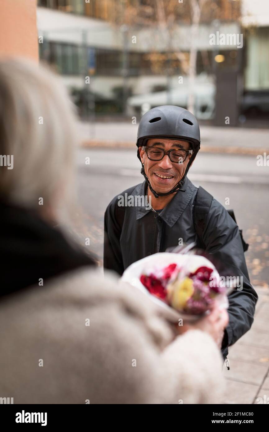 Smiling bicycle courier delivering flowers Stock Photo
