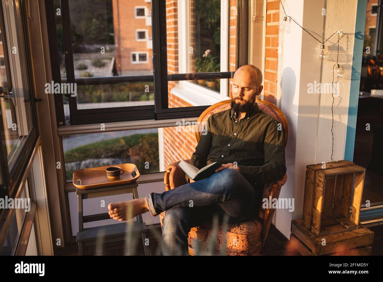 Man reading book on balcony Stock Photo
