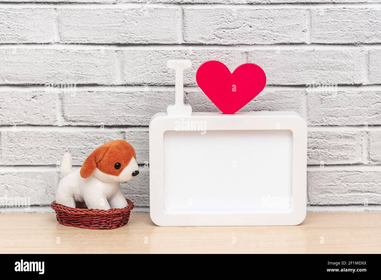 Toy puppy pet in a basket next to a frame with the inscription I and red heart and copy space for your text. Concept Valentines day or National love y Stock Photo