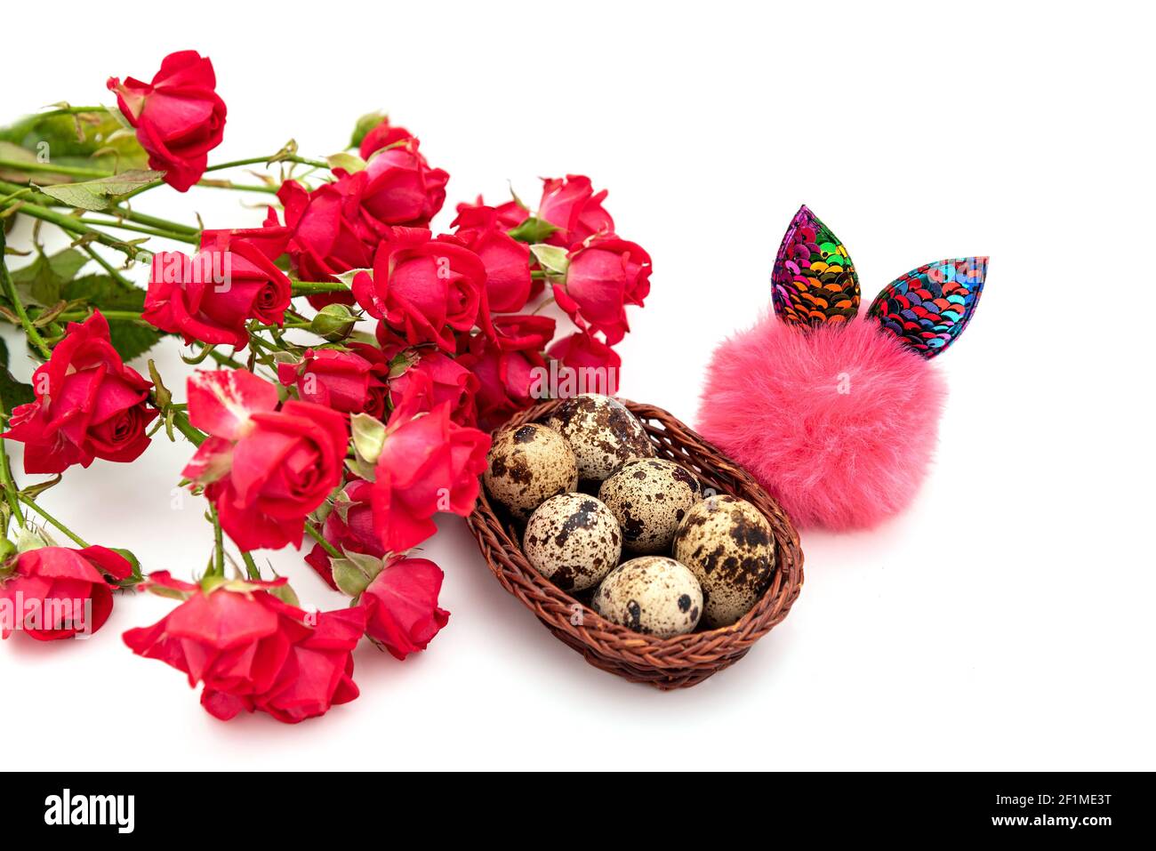 A bouquet of red roses, a small wicker basket with quail eggs and a fluffy toy with shiny rabbit ears. Isolated on white composition on the theme of t Stock Photo