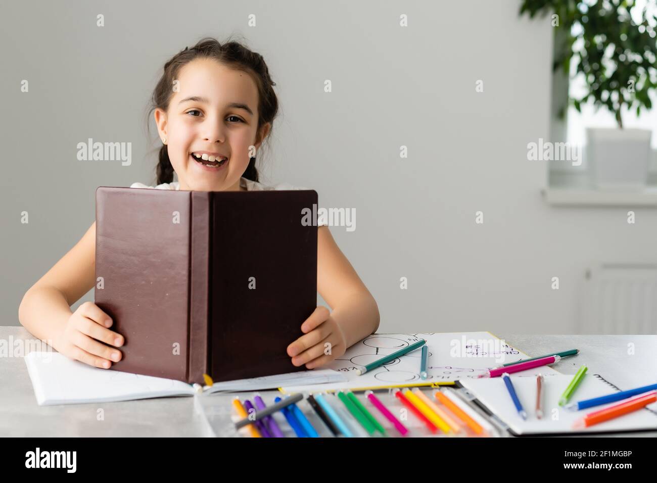 Cute little girl studying at home and smiling Stock Photo - Alamy