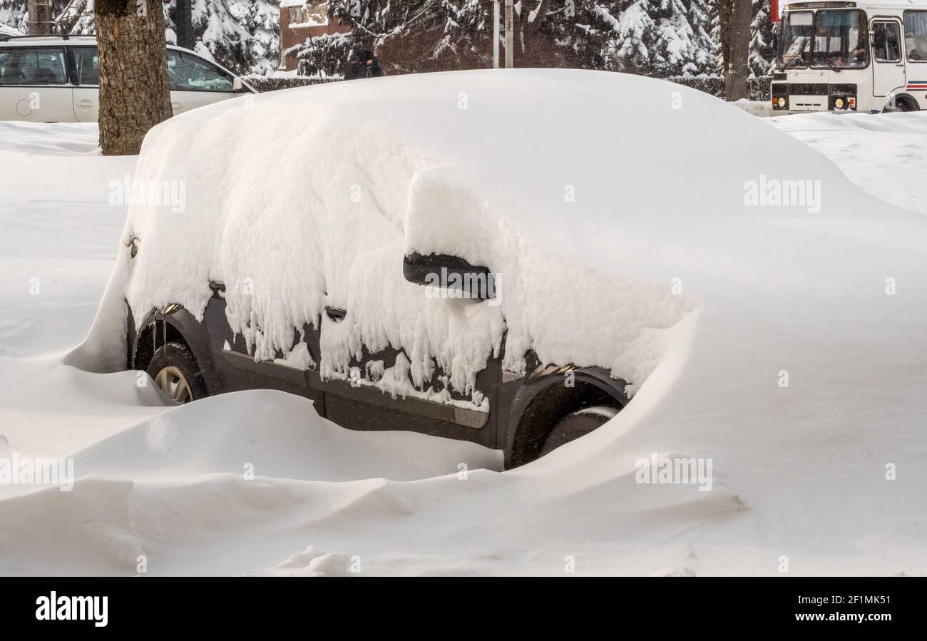 City street after blizzard. Stuck cars under the snow and ice. Buried