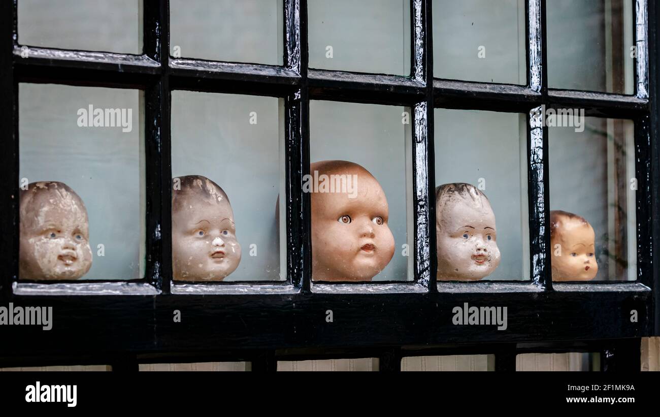 Collection of five old doll heads in a row in a window Stock Photo