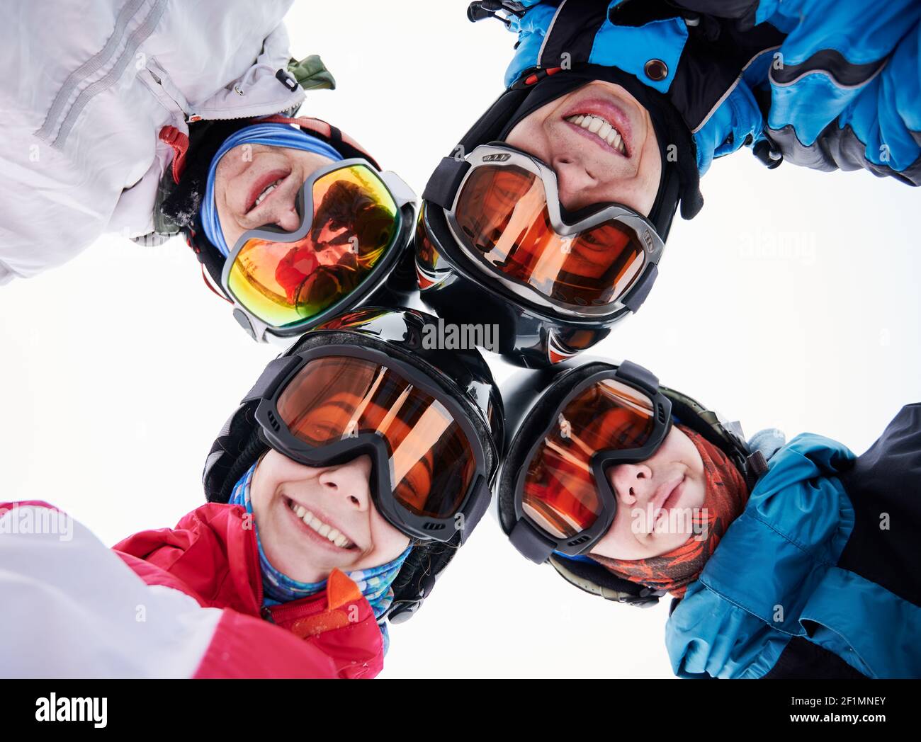 Close up of happy friends skiers in ski glasses touching heads and  expressing positive emotions. Group of joyful people wearing ski helmets  and goggles. Concept of friendship and skiing Stock Photo -