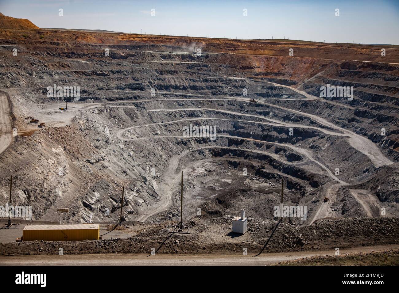 Copper ore open-pit mining (quarry) in steppe. White gravel road. Blue sky background. Stock Photo