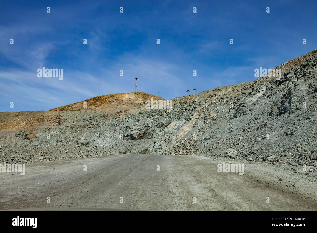 Copper ore open-pit mining. Quarry panorama. Green ground, gravel road on blue sky background. Communication tower and lighting mast. Stock Photo