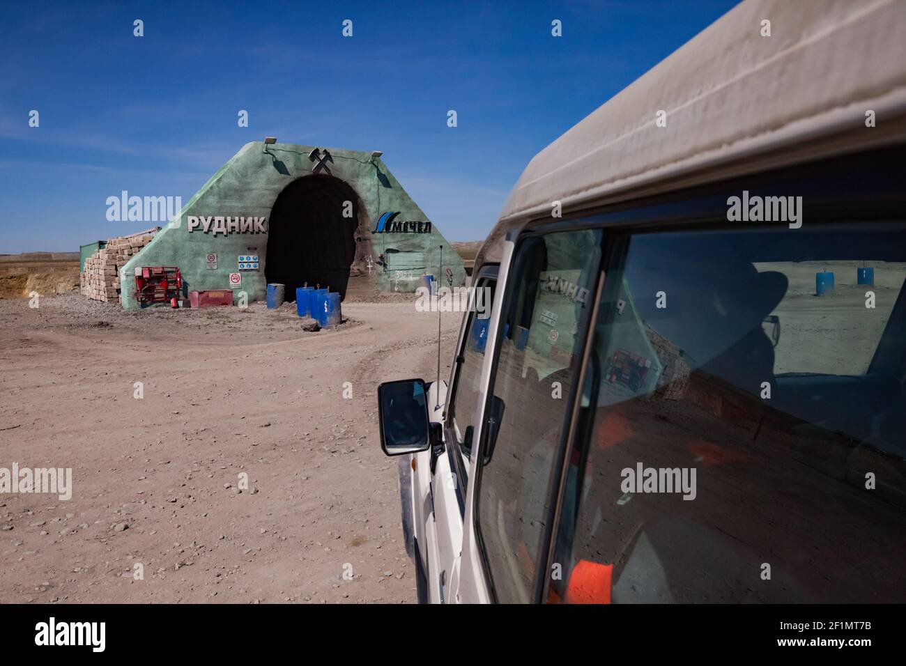 Khromtau, Aktobe region, Kazakhstan - May 06 2012: Gold ore mine portal. Title: 'Quarry' and Mechel company logo. Blue sky and desert. Off-road car on Stock Photo