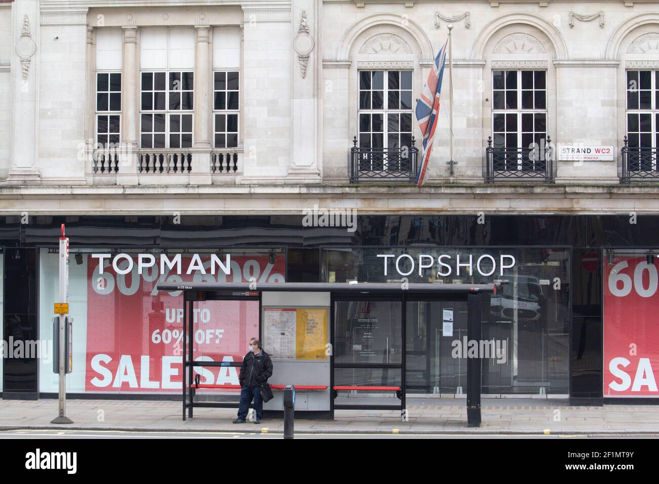 Closed shops in London, Topshop and Topman branch with bus stop in foreground with man wearing PPE mask, Strand, London ex subsidiary of the Arcadia Group went into administration in late 2020. The brand was sold to ASOS  in February 2021 Stock Photo