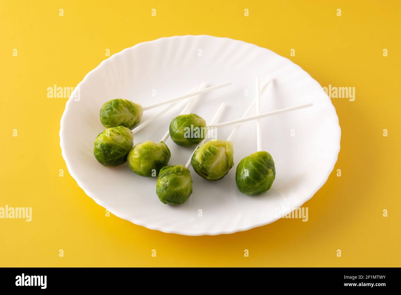 Set of brussel sprouts with lollipop sticks on yellow background Stock