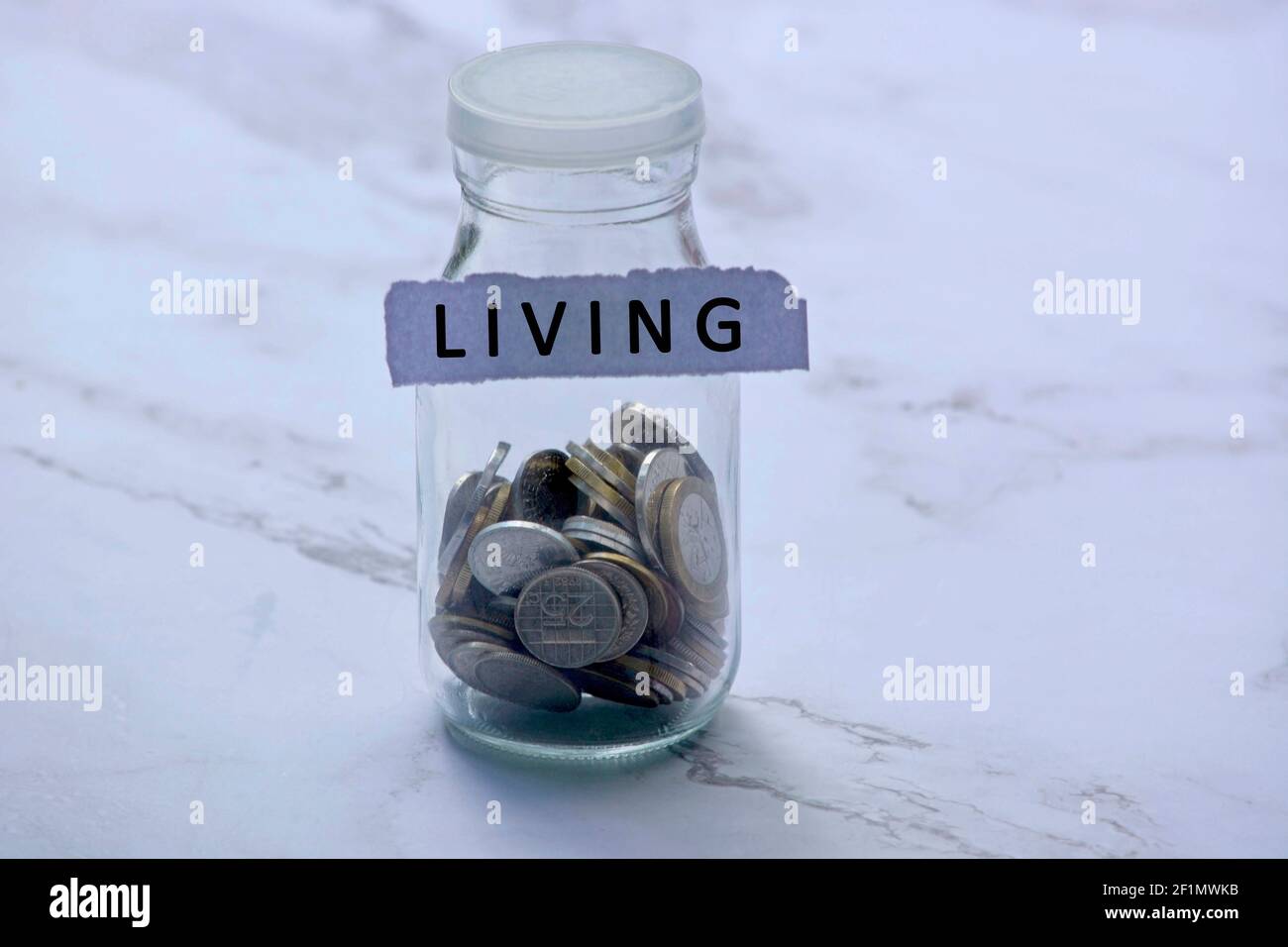 Blurred background of glass jar with multicurrency coins and text on white torn paper - Living Stock Photo
