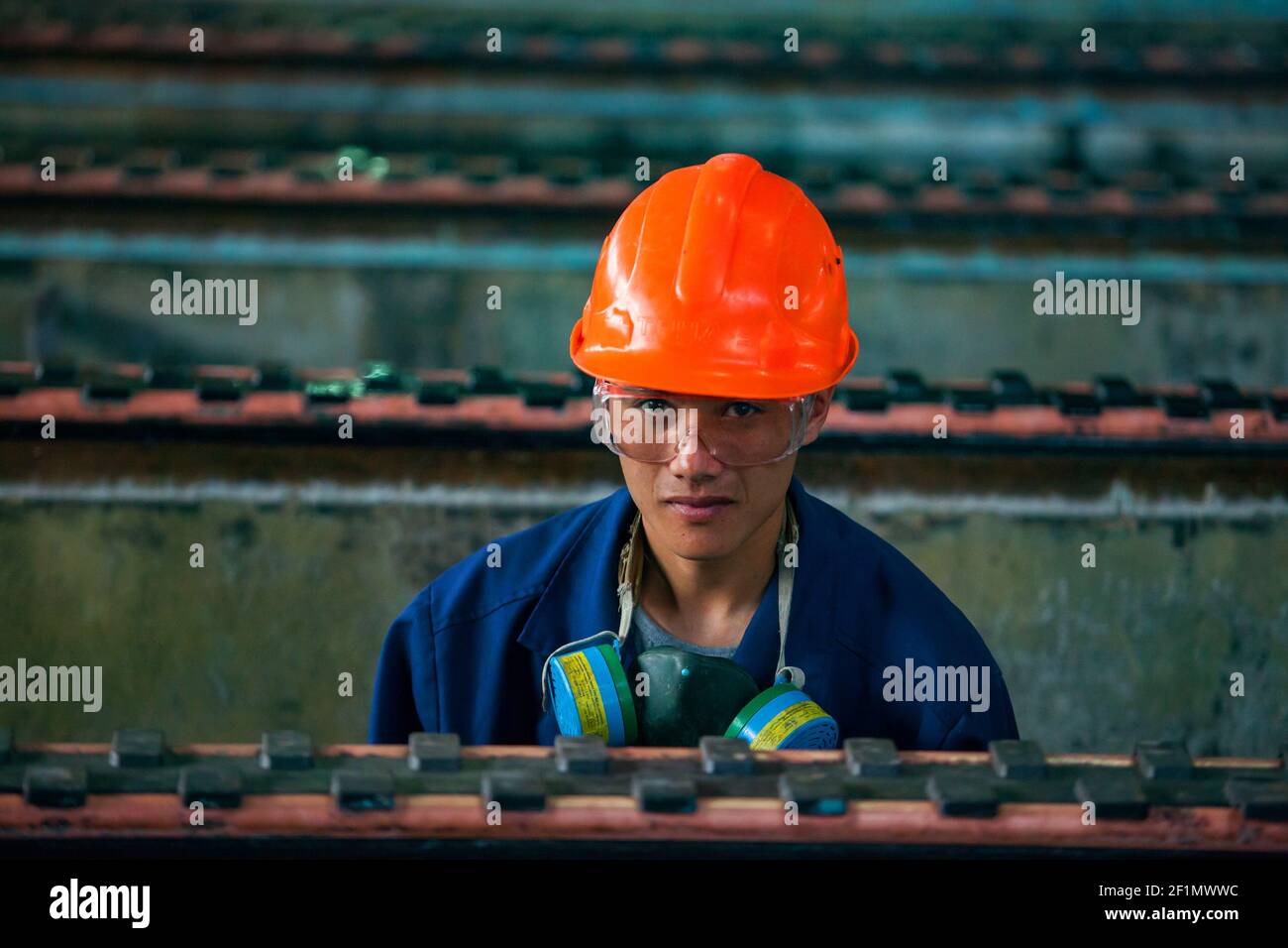 Copper metallurgical plant. Young Asian worker cleaning electrolysis bath. Stock Photo