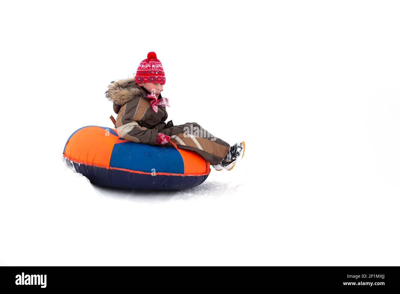 Child in winter. Cheerful boy is riding an inflatable sled Stock Photo ...