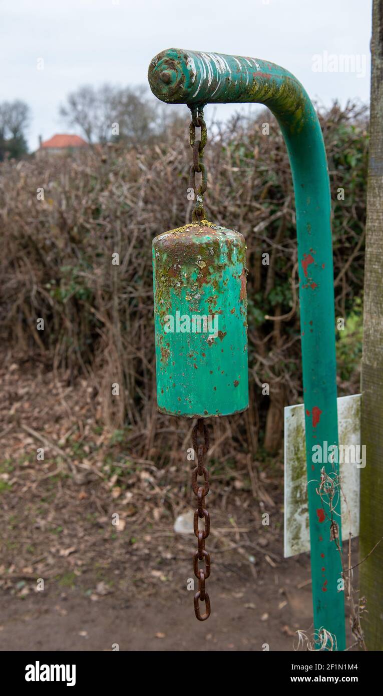 Green warning bell hanging from a metal support at the point where a