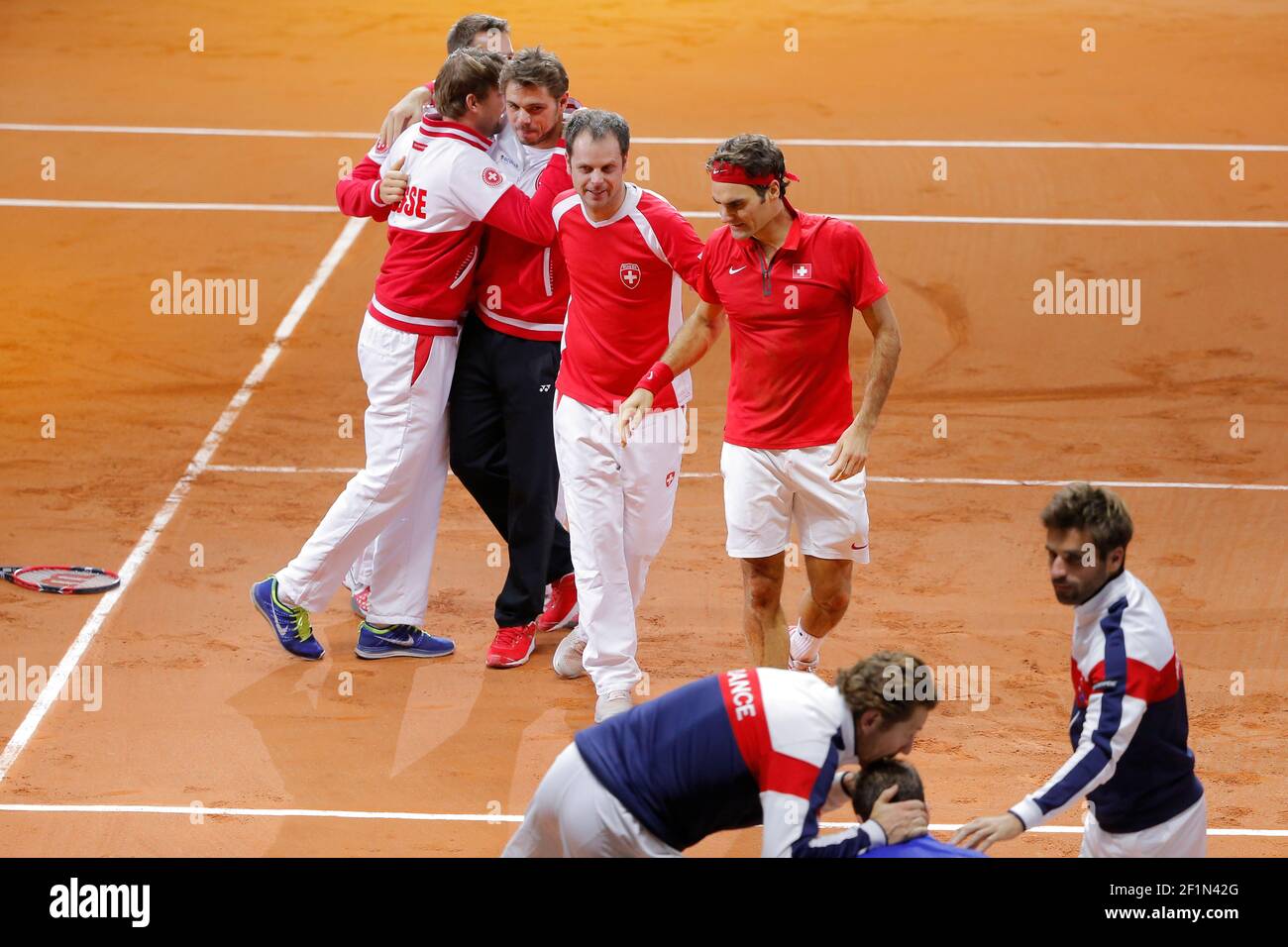 Roger Federer (SUI) and Swiss Captain Severin Luthi with Stanislas Wawrinka  (SUI) and team celebrated the victory, Lionel Roux (FRA) and Arnaud Clement  (FRA) gave confort to Richard Gasquet (FRA) during the