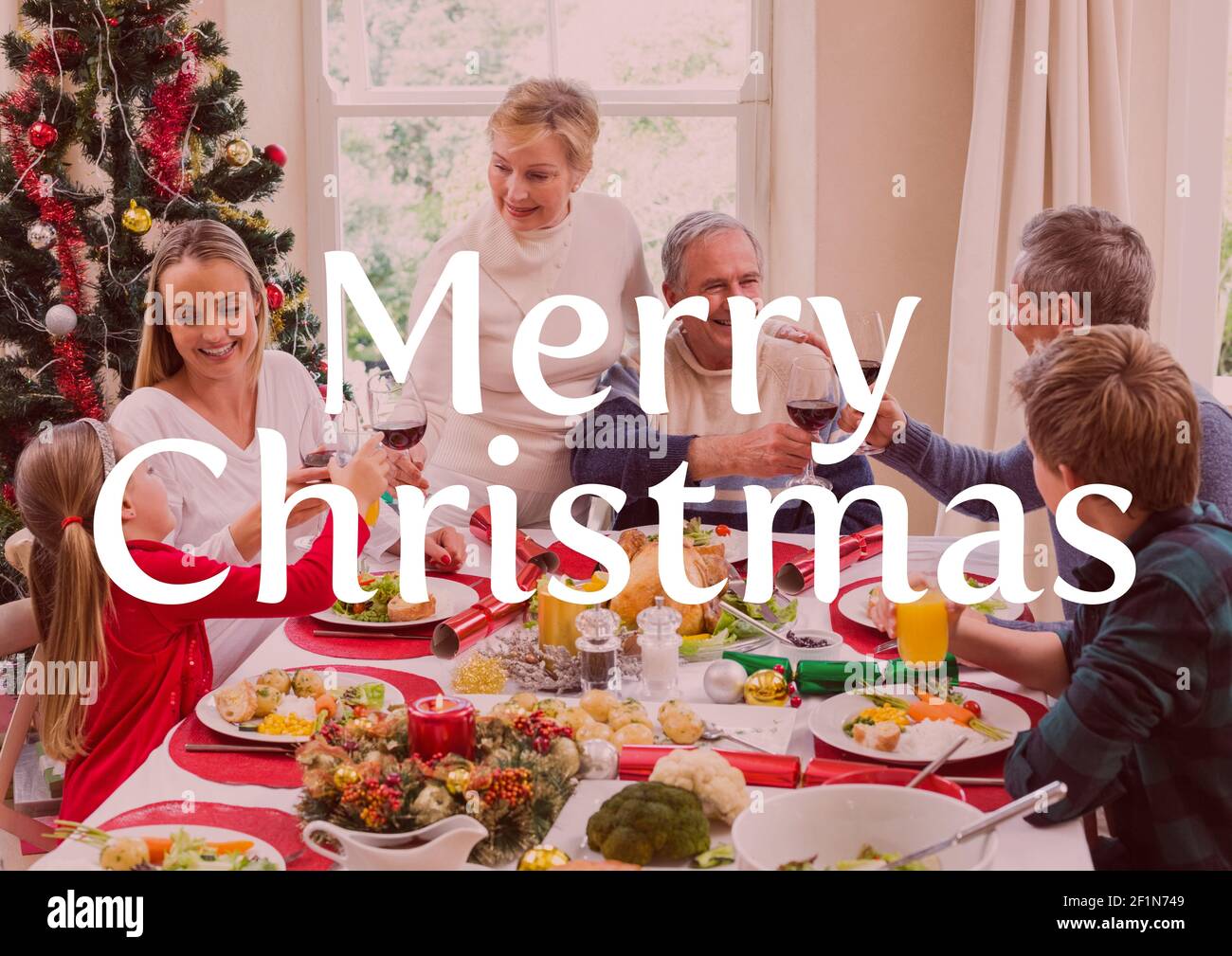 Merry christmas text over multi generation family having christmas dinner in background Stock Photo