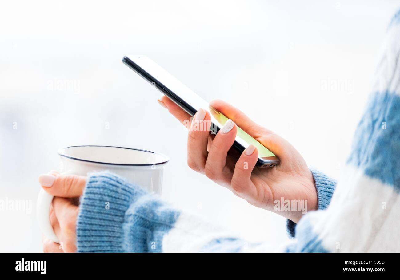 Hands holding white cup and using phone Stock Photo