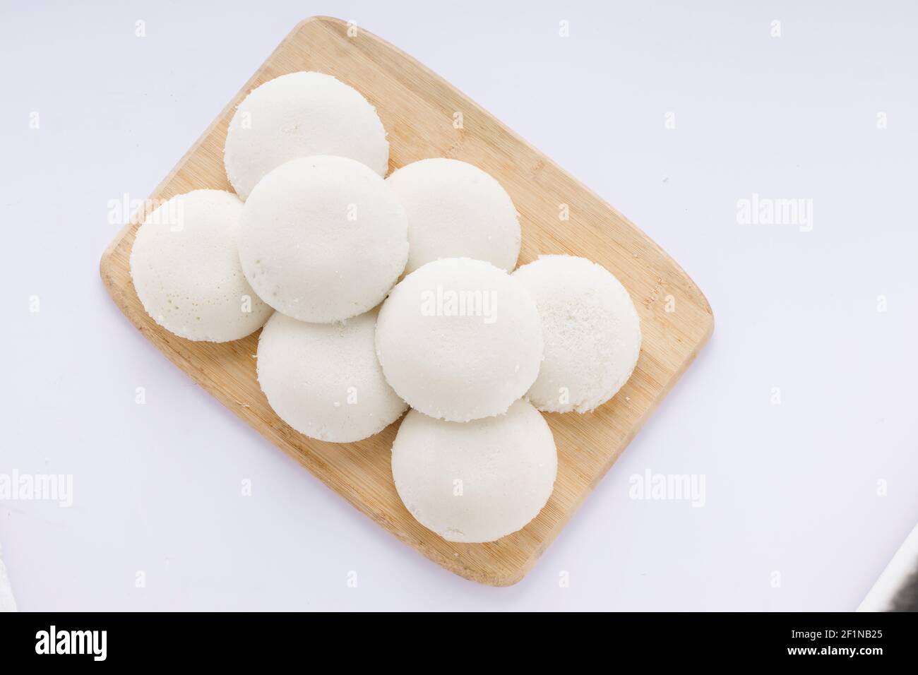 Idly or Idli, south indian main breakfast item which is beautifully arranged in a wooden base with white background. Stock Photo