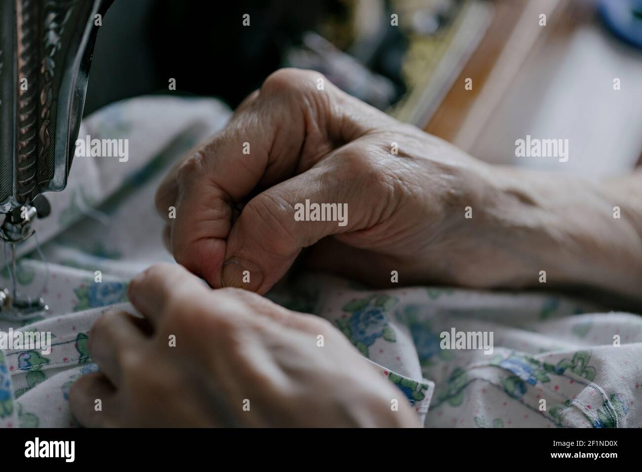 closeup of sewing on vintage sewing machine with senior female hands. selective focus photo Stock Photo