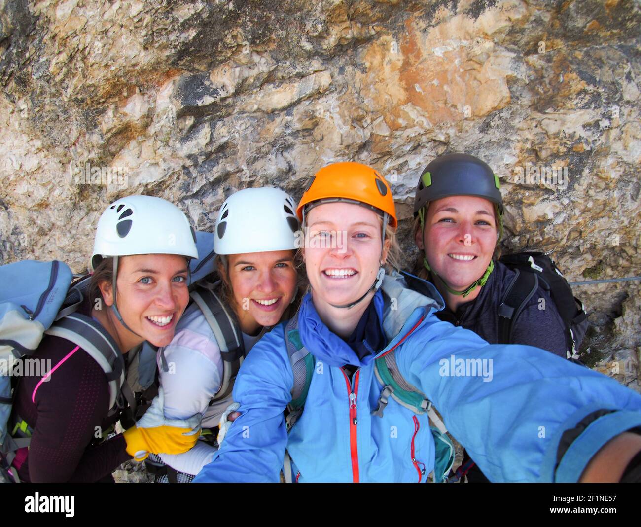 Four female climbers celebrate on the mountain summit by taking a group