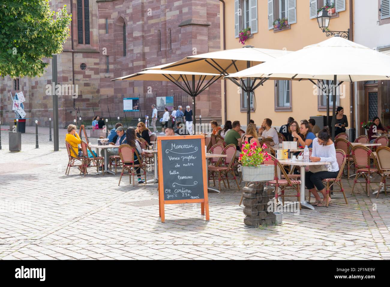 People enjoying drinks in French cafe outside of Saint Thomas' Church in the old city center of Stra Stock Photo