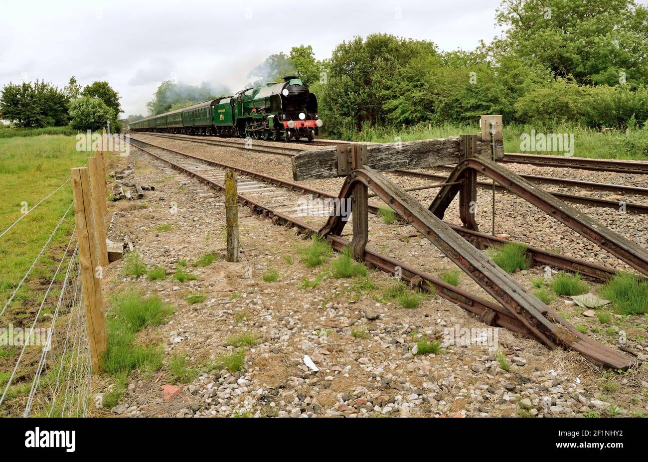 A rusty buffer stop marks the end of the siding at Great Bedwyn, as the Cathedrals Express passes on its way to Bristol. Stock Photo