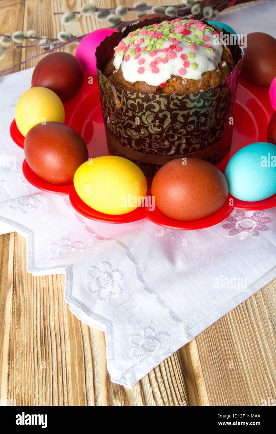 Glazed Easter cake on a red plate with colored eggs . Stock Photo
