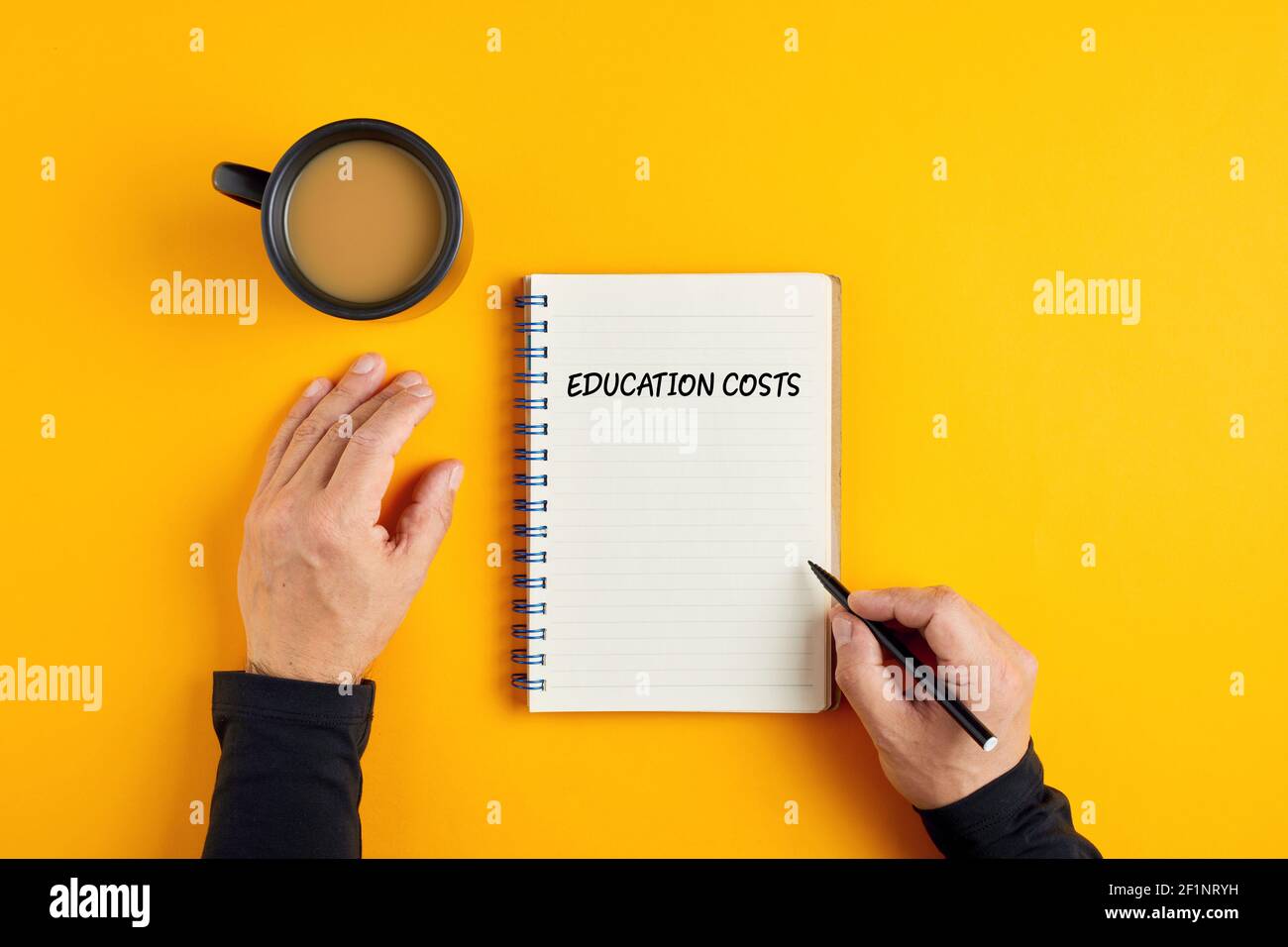 Hands of a man ready to write in his notebook the education costs. Calculating the budget for education. Stock Photo