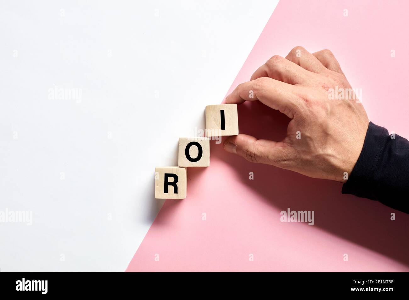 Male hand arranging the wooden cubes with the acronym ROI return on investment. ROI progress, increase concept. Stock Photo