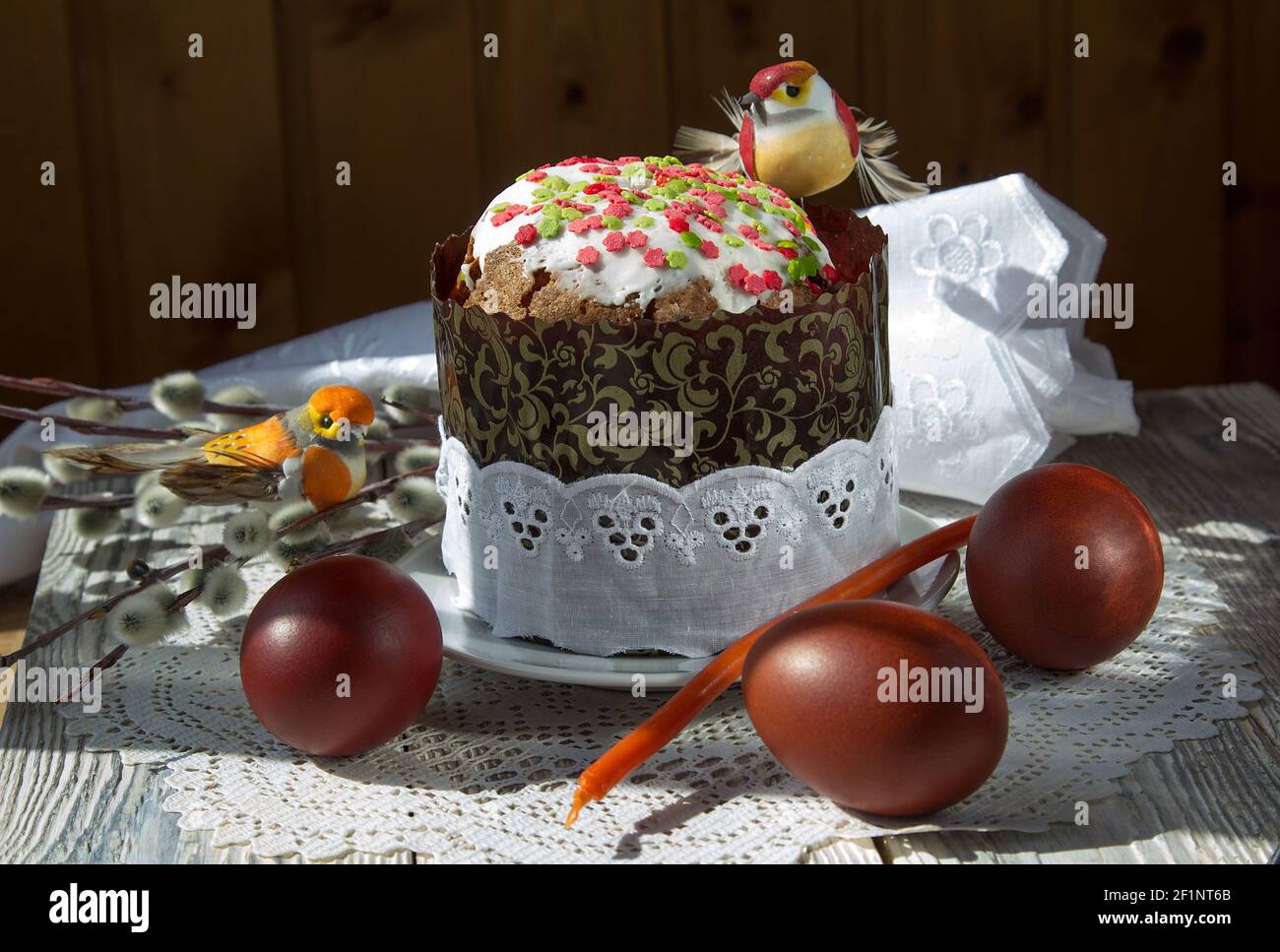 Easter cake with toy birds and painted eggs on a lace napkin. Stock Photo