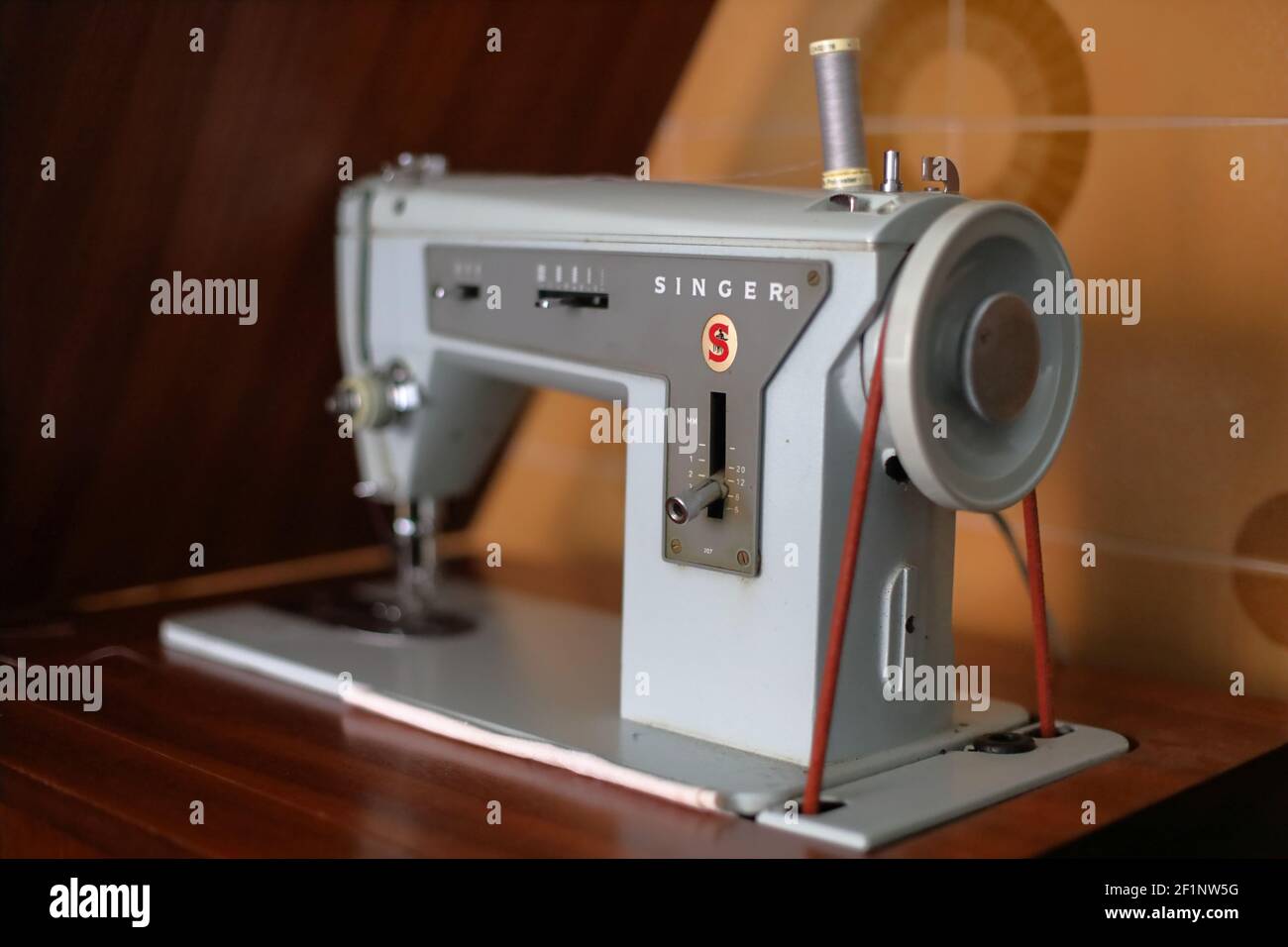 Man's feet at pedal of industrial sewing machine stock photo - OFFSET