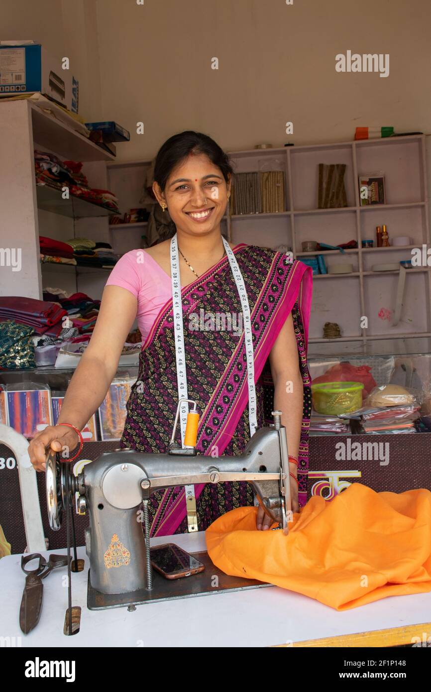 Portrait of Indian woman tailor with measuring tape standing her workshop Stock Photo