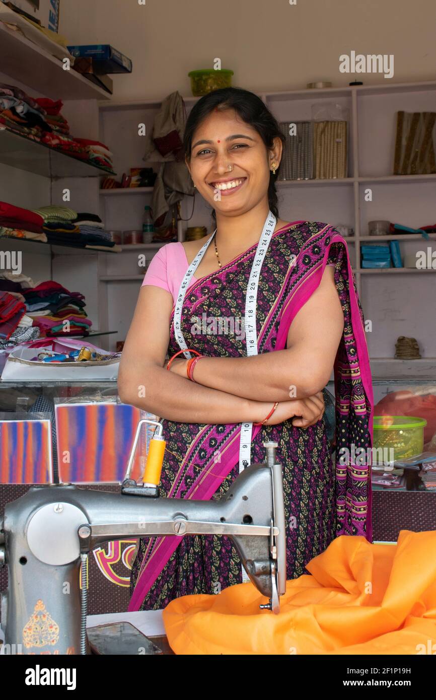 Portrait of Indian woman tailor with measuring tape standing her workshop Stock Photo
