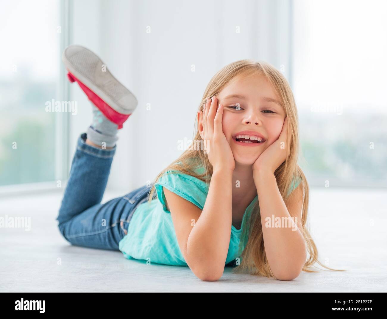 Cheerful little girl lying on a floor Stock Photo Alamy