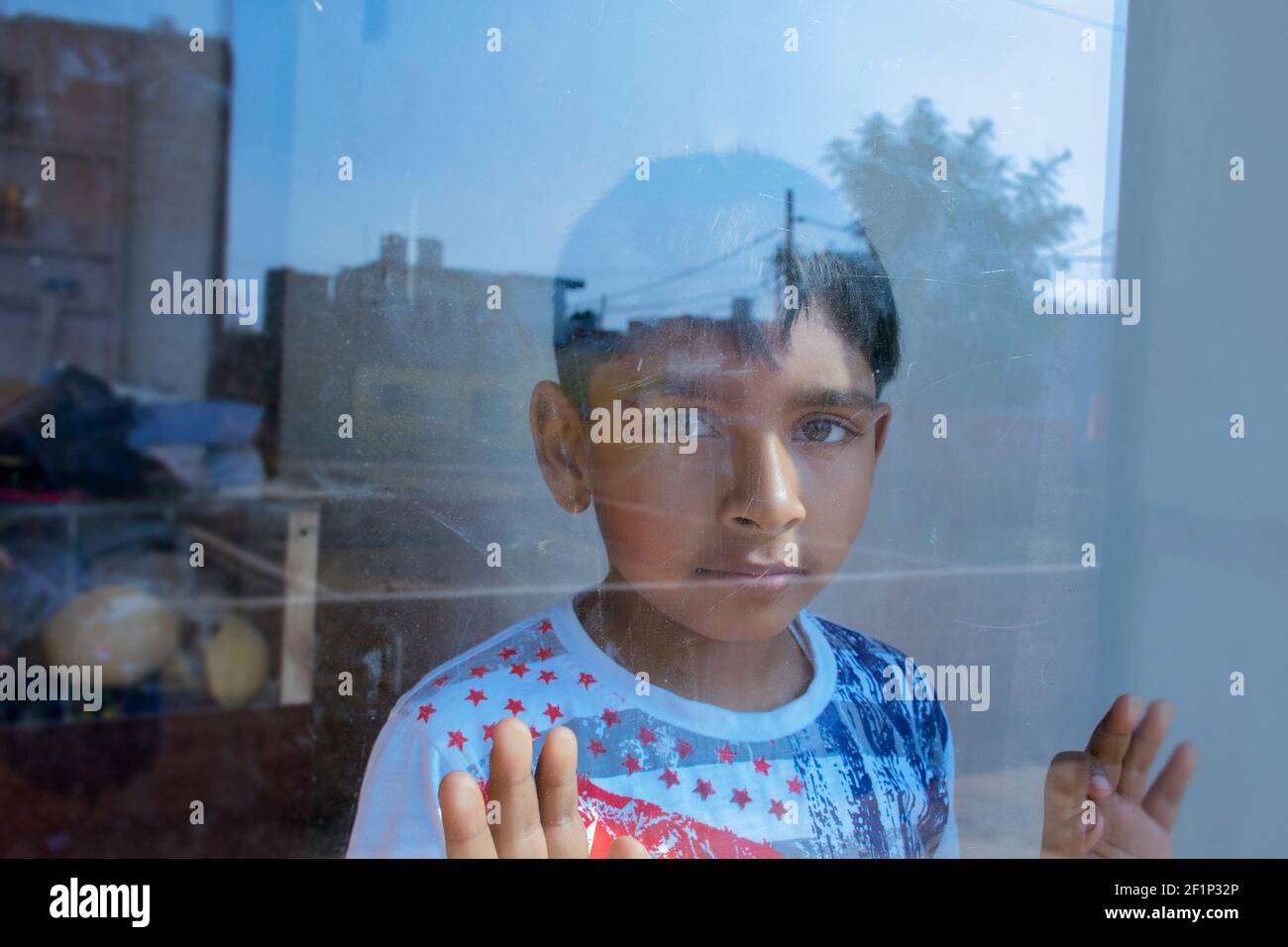 young boy looking through glass window Stock Photo - Alamy