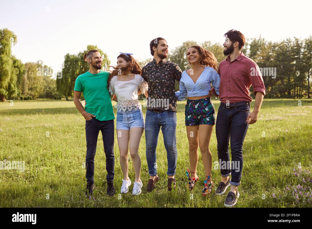 Millennial friends enjoying their time outdoors. Cheerful girls and guys spending summer day in countryside Stock Photo