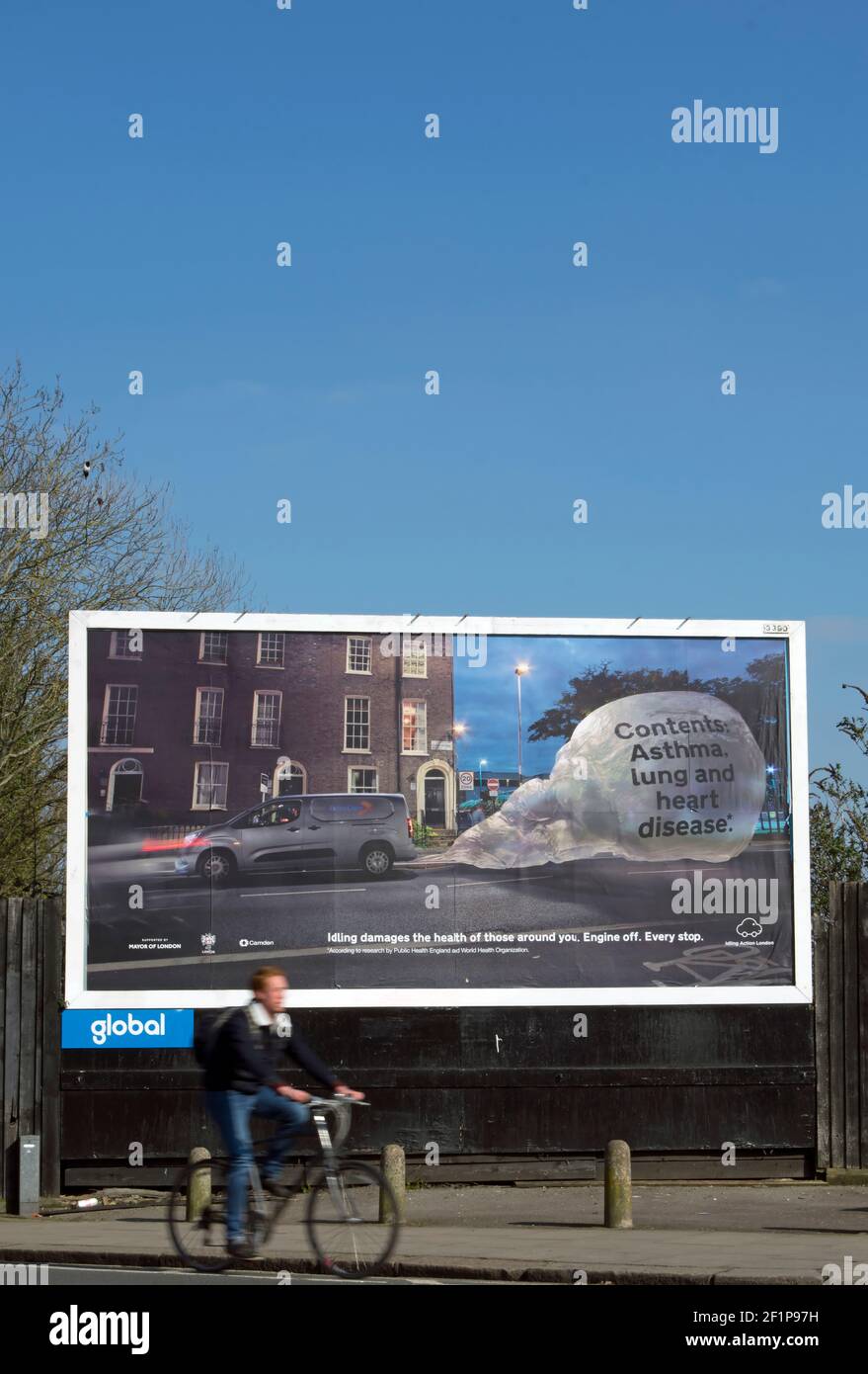 a cyclist passes a billboard warning of the pollution and threat to public health caused by engine idling, in twickenham, middlesex, england Stock Photo