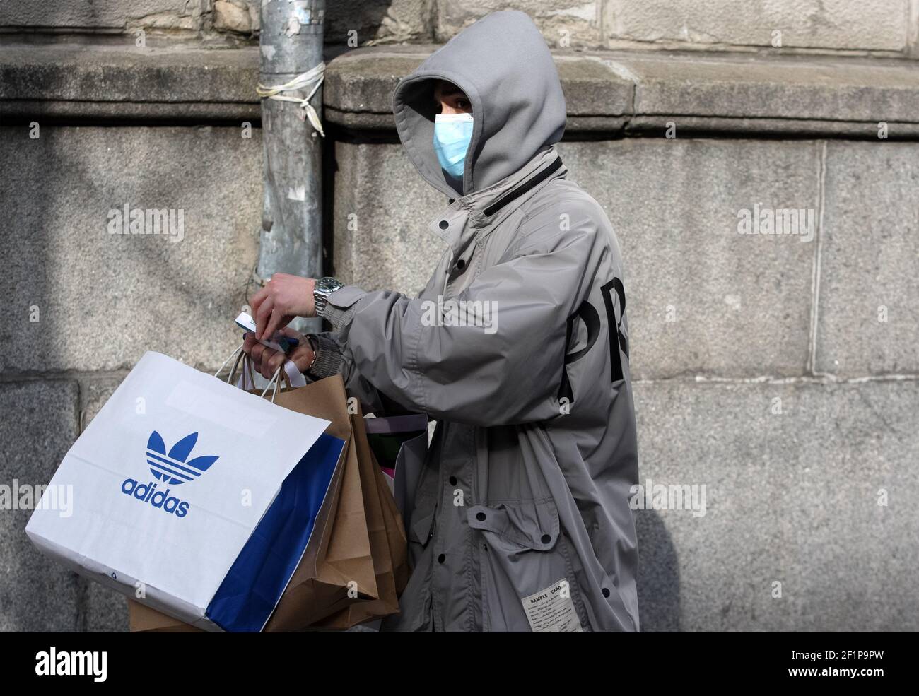 Kiev, Ukraine. 6th Mar, 2021. A shopper wearing a face mask as a precaution  against the spread of covid-19 seen holding a shopping bag with Adidas logo  on a street in Kiev.