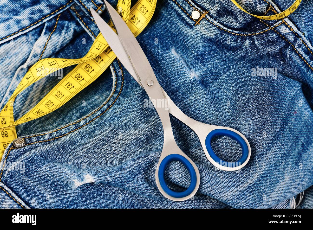 Closeup tailor hand use measuring tape to measure width of jeans